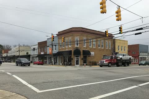 Brick storefronts at a downtown intersection in Angier, with traffic signals overhead