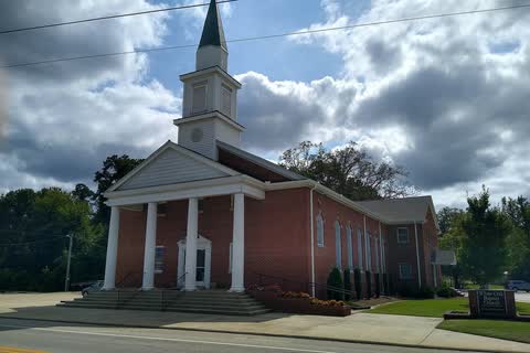 Red-brick church with a white columned portico and steeple beside a road in Archer Lodge