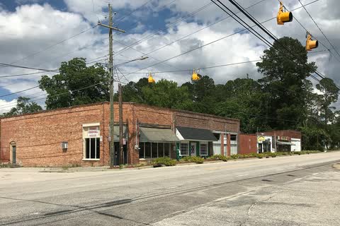 A row of one-story brick storefronts at an intersection in Autryville