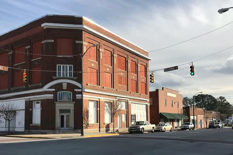 A three-story red-brick commercial building at a corner in downtown Ayden