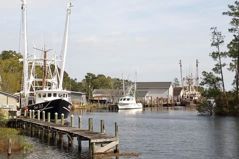 Fishing trawlers tied up along wooden docks on the Bay River at Bayboro