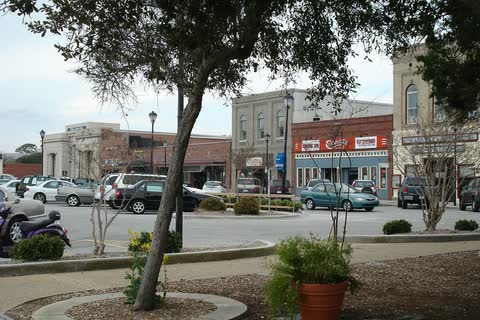 Historic commercial buildings and parked cars beyond a small planted median in downtown Beaufort