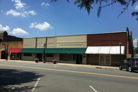 Row of one- and two-story brick storefronts with awnings along West Virginia Avenue in Bessemer City