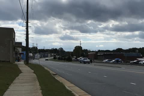 Main road through Biscoe with low brick buildings and parked cars under clouds