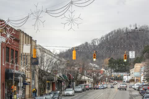 Shops and parked cars along King Street in downtown Boone with a wooded mountain behind