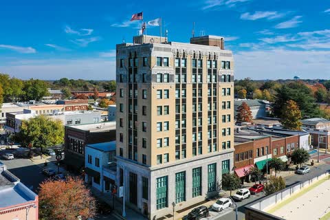 Aerial view of a tall historic office building above the low roofs and trees of downtown Burlington