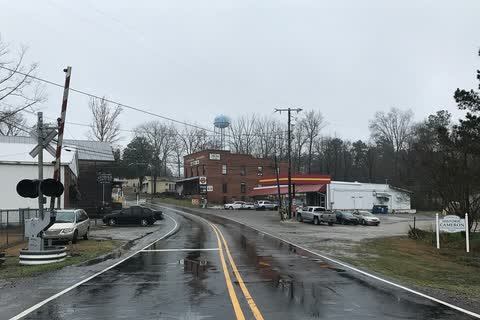 Road through Cameron with a railroad crossing, brick buildings and a water tower