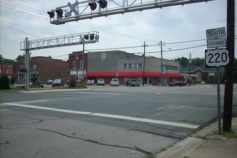 Railroad crossing signals in front of commercial buildings in central Candor