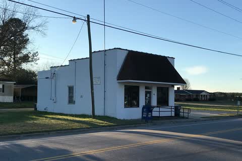A small white post office building beside a road in Castalia