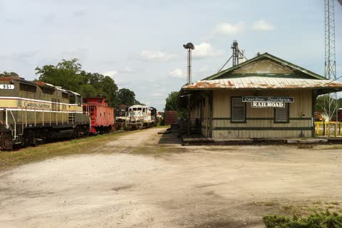 A small wooden railroad depot with parked locomotives and freight cars in Chadbourn