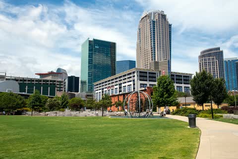Office towers of Uptown Charlotte behind a grassy park on a sunny day