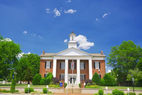 Brick Polk County Courthouse with white columns and a cupola in Columbus