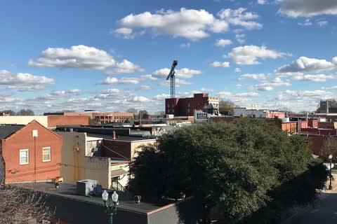 Rooftops and brick buildings of downtown Concord under a blue sky with scattered clouds