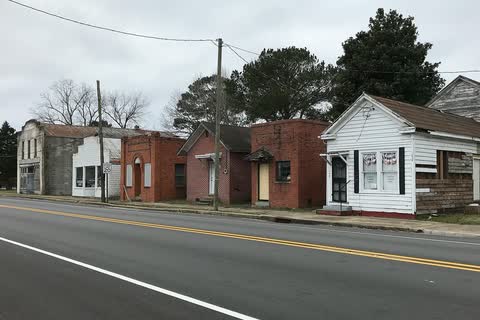 A row of small brick and white wooden commercial buildings along a road in Conway