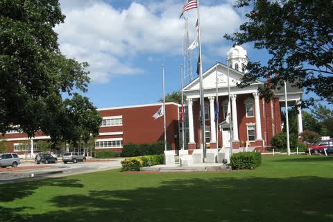 A white-columned courthouse entrance with flags on a lawn in Beaufort, North Carolina