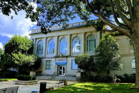 Neoclassical 1924 Catawba County Courthouse with tall arched windows behind trees in Newton