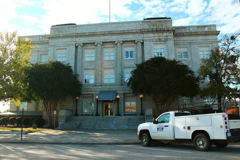 A pale stone courthouse behind trees in Fayetteville, North Carolina