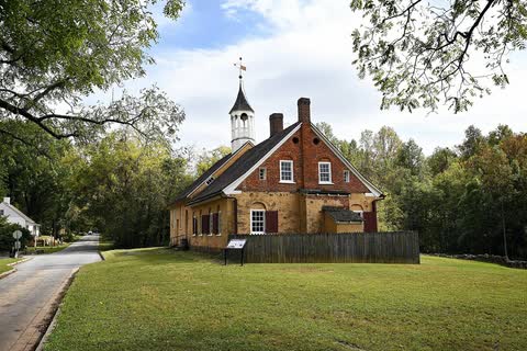 Small 18th-century stone and brick church house with a white belfry on a green lawn