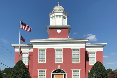A red-painted brick courthouse with a white cupola in Oxford, North Carolina