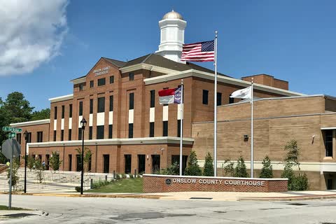 A brick courthouse with a white cupola and flags in Jacksonville, North Carolina