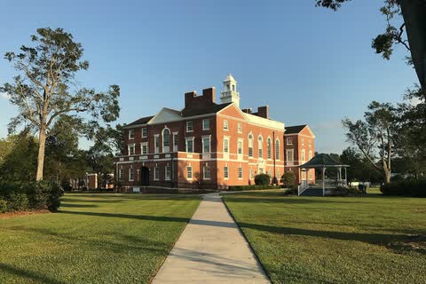 A brick courthouse with a white cupola at the end of a long walkway in Burgaw, North Carolina