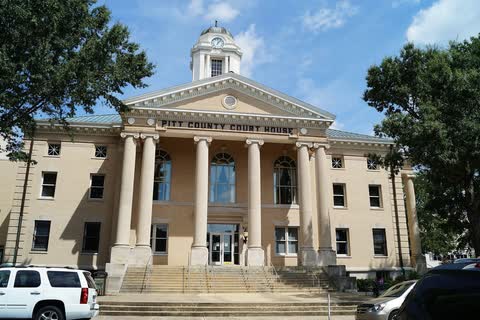 A pale stone courthouse with columns and a clock cupola in Greenville, North Carolina