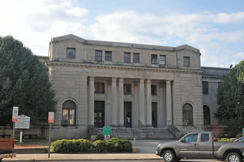 Pale stone courthouse with a row of columns behind front shrubs
