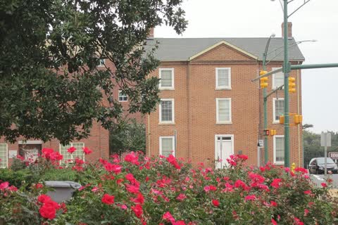 Red brick historic Monroe City Hall behind a bed of red roses