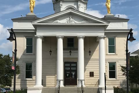 A white classical city hall with a cupola and statues on its roof in Goldsboro, North Carolina