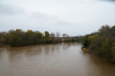 Wide brown Yadkin River flowing between wooded banks under a gray sky
