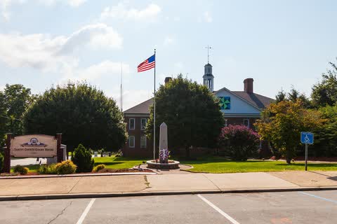 Brick courthouse with a white cupola behind a flagpole, a monument and a Yancey County Court House sign