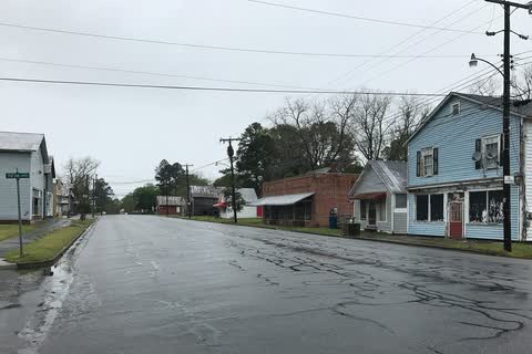 A wet street lined with older wooden and brick commercial buildings in Creswell