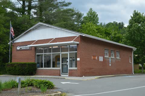 Brick Crossnore post office with a flagpole among trees