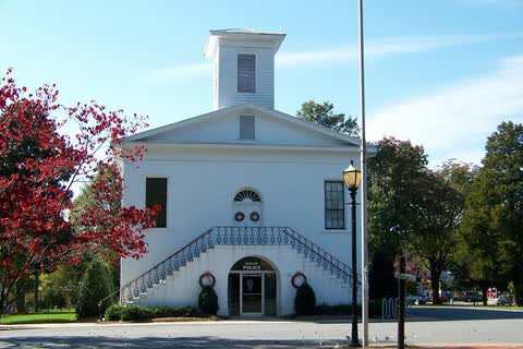 White two-story former courthouse with a cupola and twin front stairs in Dallas