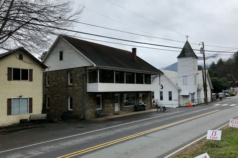 Stone Greystone Lodge building with a long porch on a Dillsboro street