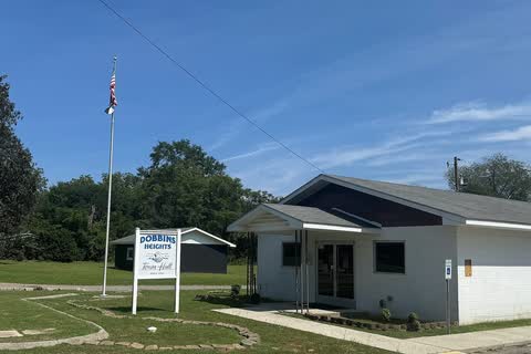 Dobbins Heights Town Hall, a small white building with a sign and a flagpole on a lawn