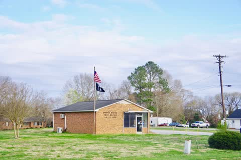 Small brick Earl post office with a flagpole and lawn