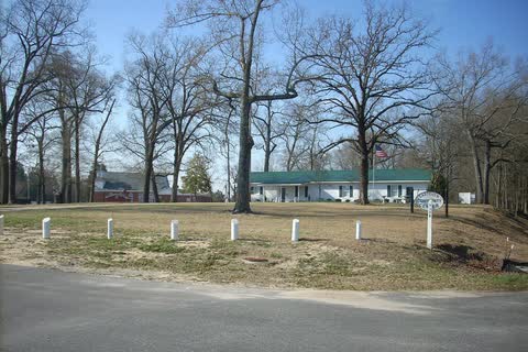 A low community center building set back behind a lawn and bare trees in Eastover
