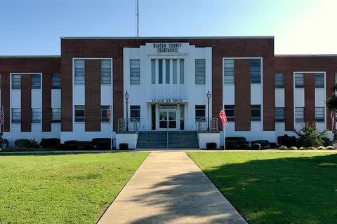 A wide brick courthouse with a white central entrance behind a lawn in Elizabethtown