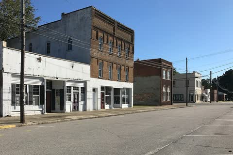 Two- and three-story brick and stucco commercial buildings along a quiet street in Elm City