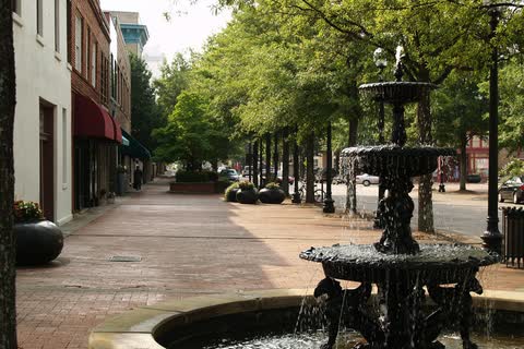 Tree-lined brick sidewalk on Hay Street with an iron fountain in the foreground