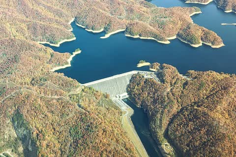 Aerial view of Fontana Dam holding back blue Fontana Lake among autumn mountains