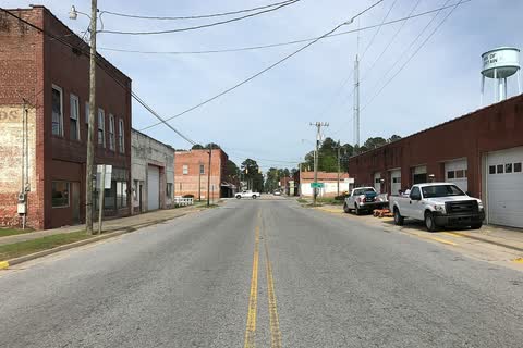 A two-lane street with brick buildings and the town water tower in Fountain