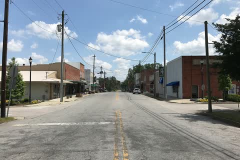 One-story storefronts along a wide street in Four Oaks
