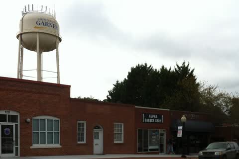 Water tower lettered Downtown Garner rising behind a row of one-story brick storefronts