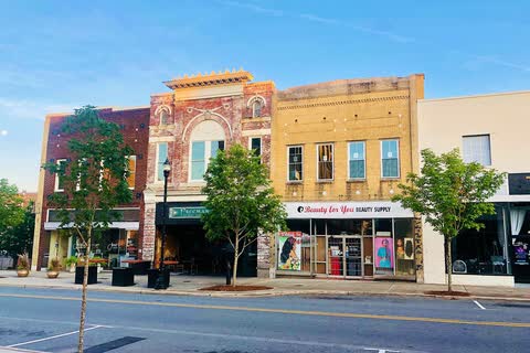 Row of restored brick storefronts with street trees along Main Street in Gastonia