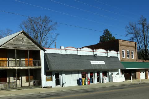 Old commercial buildings beside a two-lane road and the railroad tracks in Goldston