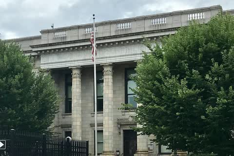 The columned stone Alamance County Courthouse in Graham, with a flagpole and trees in front