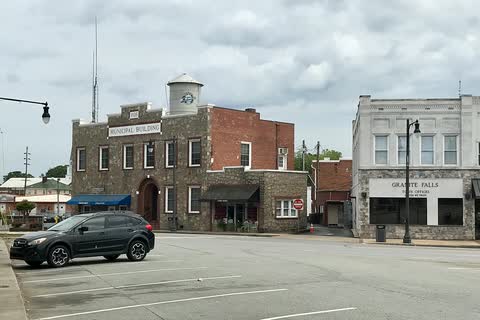 Stone municipal building, brick storefronts and a water tower in downtown Granite Falls