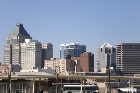 Office towers of downtown Greensboro rising behind a rail platform on a clear day
